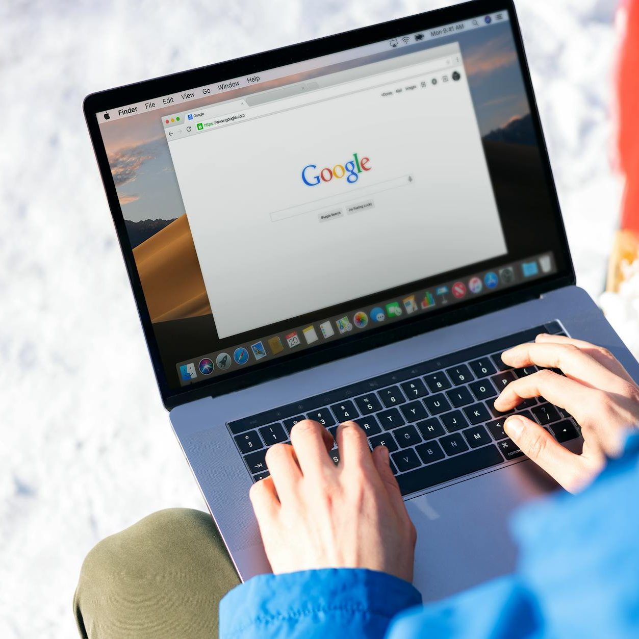 person using macbook pro with google website on screen